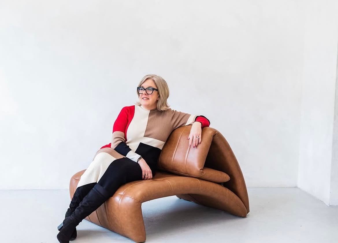 Carol Ronnell Elizabeth seated on a leather chair in a bright studio